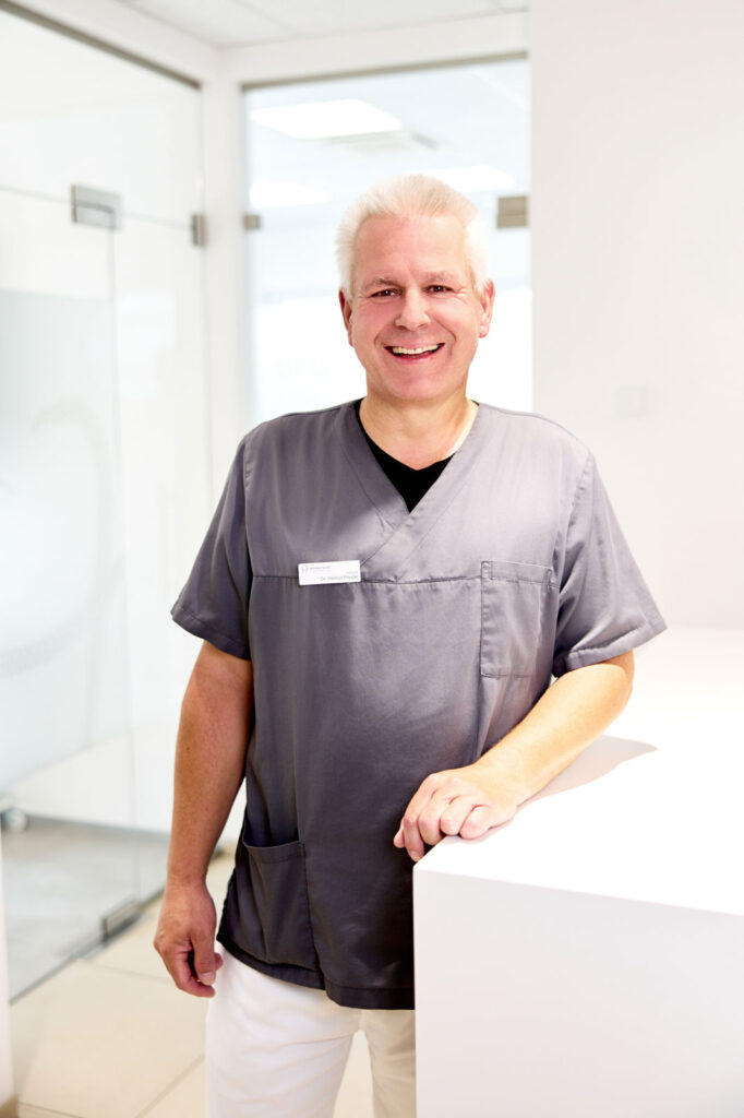 Dr. med. dent. Helmut Preidel, Zahnarzt der Praxis Dr. Herzog und Kollegen, am Empfangstresen
