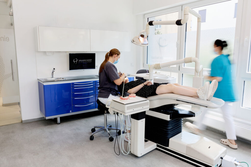 Behandlungsraum mit moderner Ausstattung, Assistentin betreut liegende Patientin